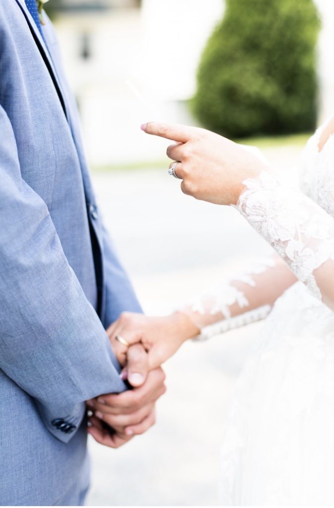 Bride holds grooms hands during their first look