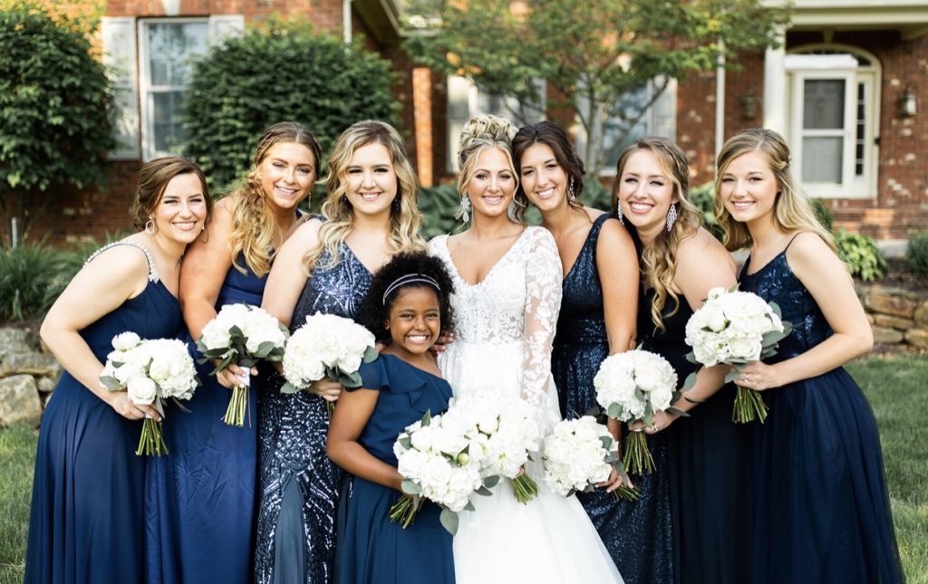 Bride stands with her bridesmaids in navy bridesmaids dresses