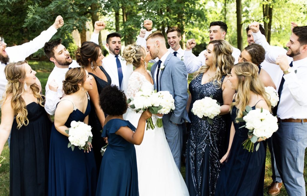 Bridal party cheers as they stand around the bride and groom