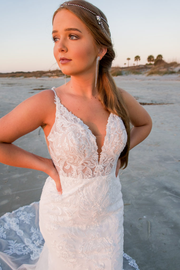 close up of lace fitted wedding dress on beach at sunrise